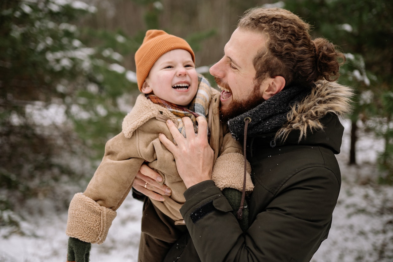 Father and son playing in the snow to represent keeping your children warm